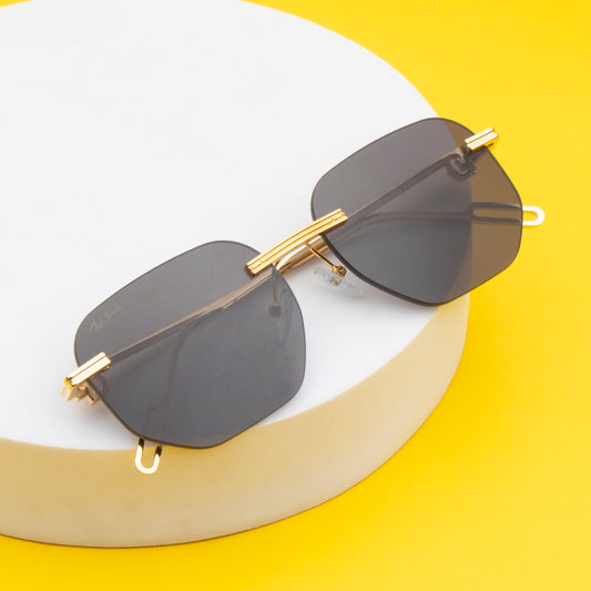 A pair of rimless, gold-frame sunglasses resting on a surface with a yellow background.